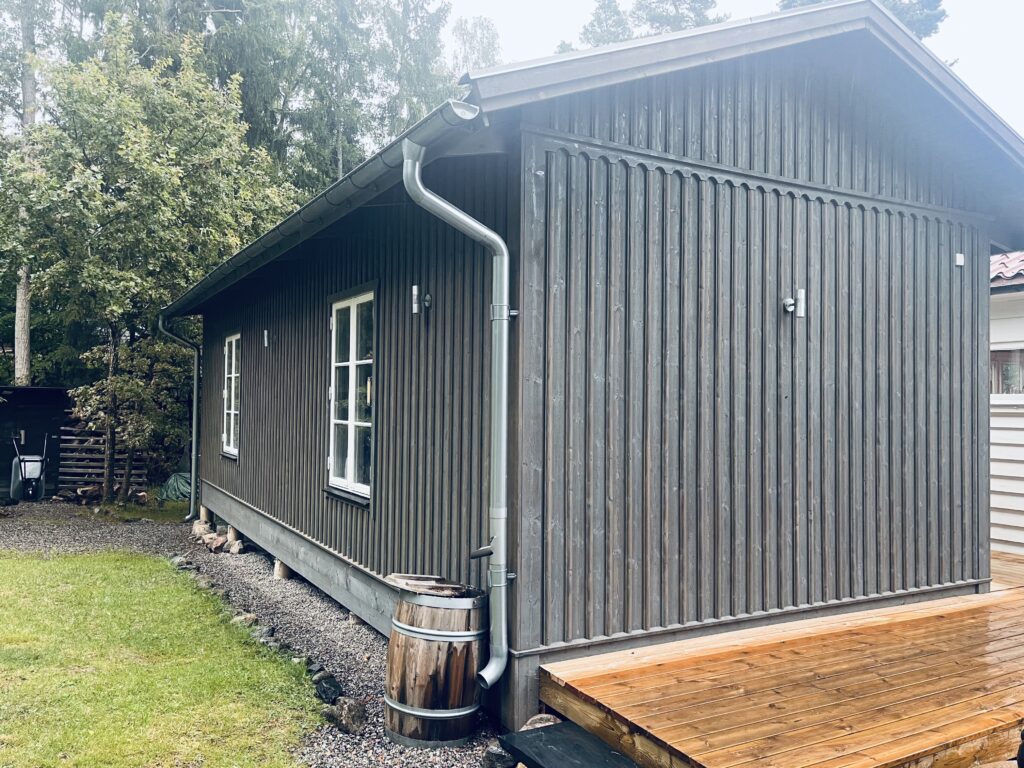 Svart trähus med stora fönster och träterass